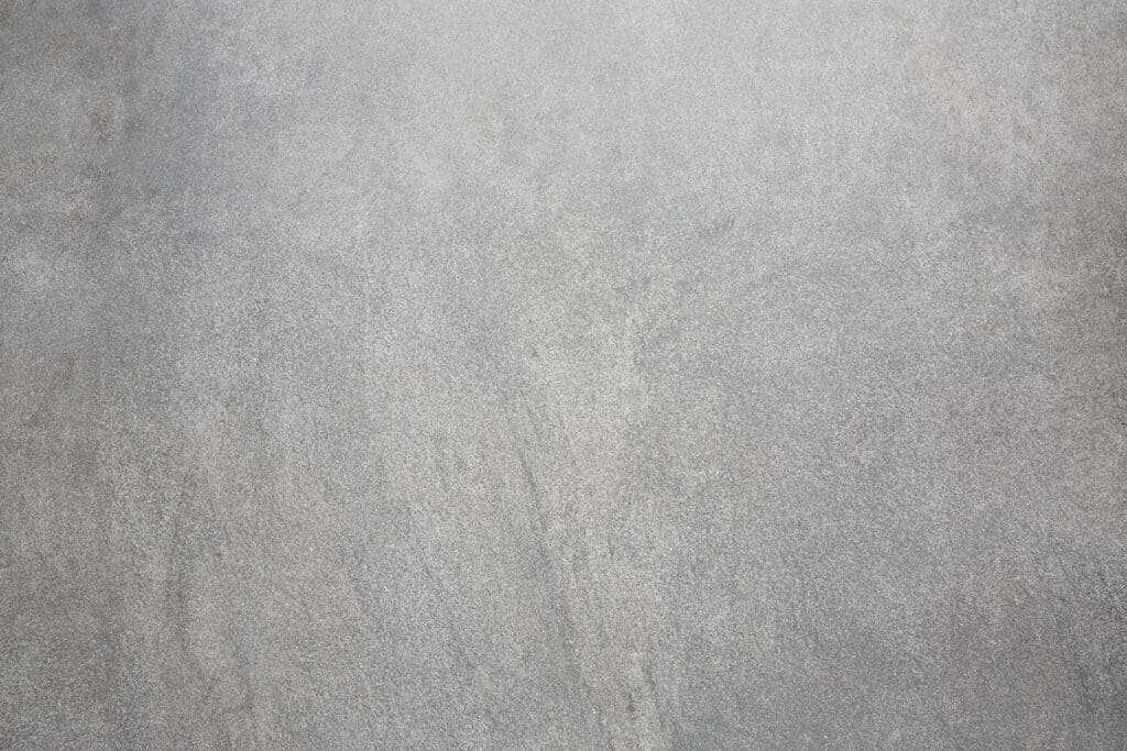 A smooth gray concrete surface with subtle texture and faint lines running across it, creating a minimalist and industrial appearance.